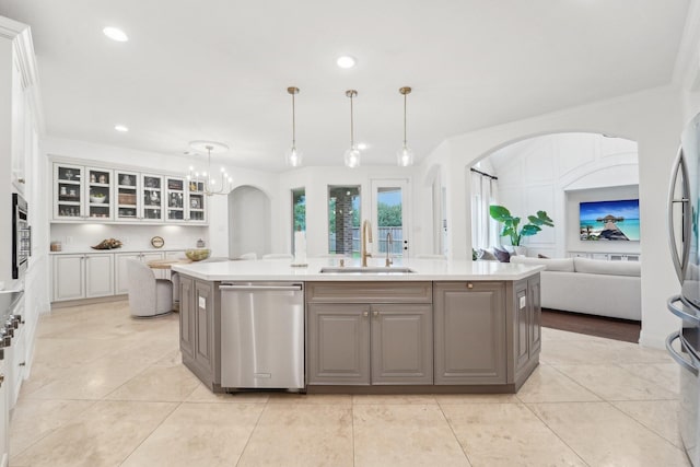 kitchen featuring gray cabinetry, stainless steel appliances, sink, hanging light fixtures, and an island with sink