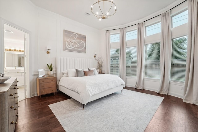 bedroom featuring dark hardwood / wood-style floors, ensuite bath, and a notable chandelier