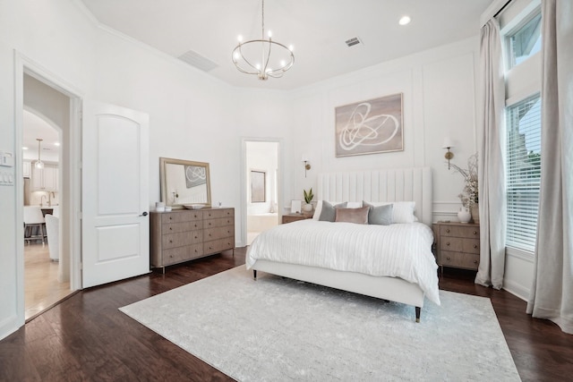 bedroom featuring dark hardwood / wood-style flooring, ornamental molding, connected bathroom, and a chandelier