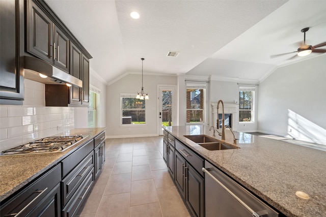 kitchen with backsplash, ceiling fan with notable chandelier, lofted ceiling, and appliances with stainless steel finishes