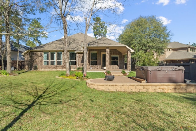 rear view of property featuring a yard, a patio, and a hot tub