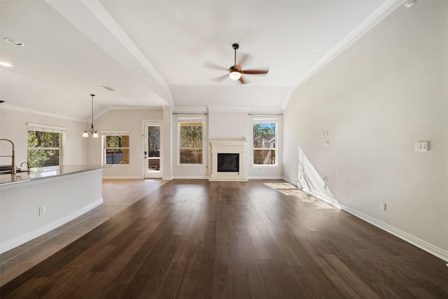 unfurnished living room with dark wood-type flooring, vaulted ceiling, plenty of natural light, and crown molding