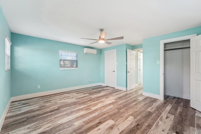 unfurnished bedroom featuring ceiling fan, hardwood / wood-style flooring, and a wall mounted air conditioner