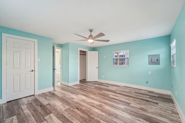 unfurnished bedroom with light wood-type flooring, ceiling fan, and electric panel