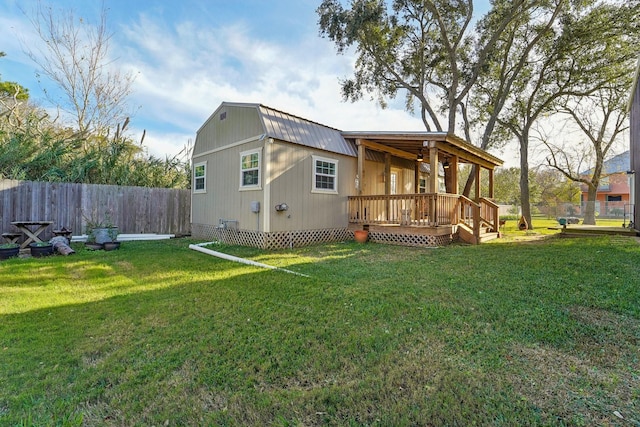 rear view of property featuring a deck and a lawn