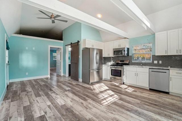 kitchen featuring white cabinets, stainless steel appliances, and a barn door