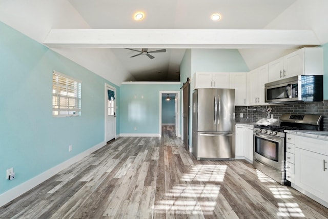 kitchen with white cabinets, appliances with stainless steel finishes, tasteful backsplash, vaulted ceiling, and ceiling fan