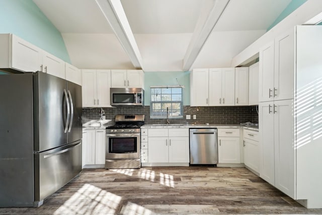 kitchen featuring white cabinets, decorative backsplash, appliances with stainless steel finishes, and sink