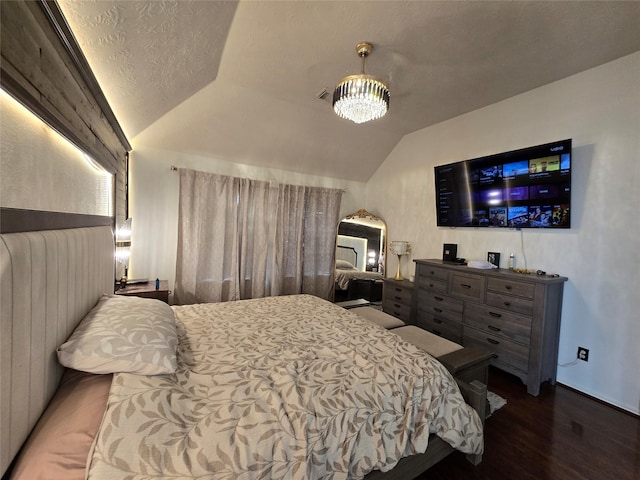 bedroom with dark hardwood / wood-style floors, lofted ceiling, and a notable chandelier