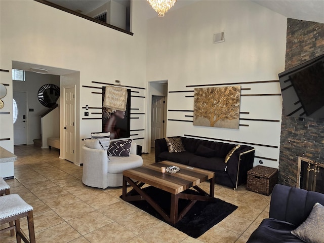 living room with a towering ceiling, a fireplace, light tile patterned floors, and an inviting chandelier