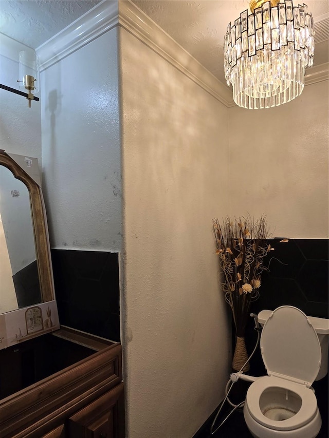 bathroom with a chandelier, toilet, and ornamental molding