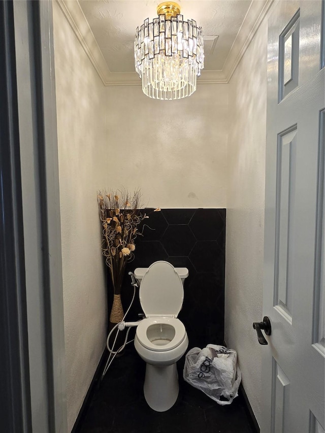 bathroom featuring a notable chandelier, toilet, and crown molding