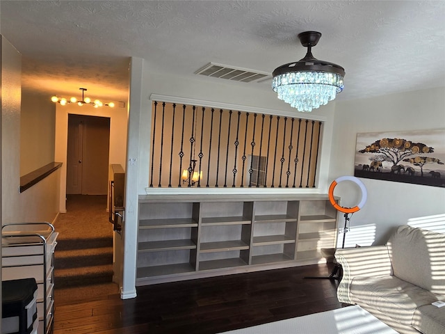 interior space with a textured ceiling, hardwood / wood-style flooring, built in features, and a notable chandelier