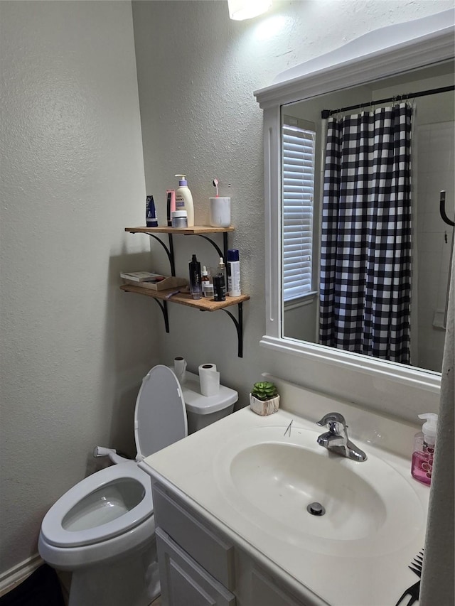 bathroom featuring vanity, toilet, and walk in shower