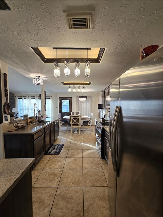 kitchen featuring sink, pendant lighting, dark brown cabinets, light tile patterned floors, and appliances with stainless steel finishes