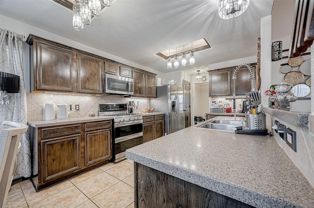 kitchen with dark brown cabinetry, hanging light fixtures, and appliances with stainless steel finishes