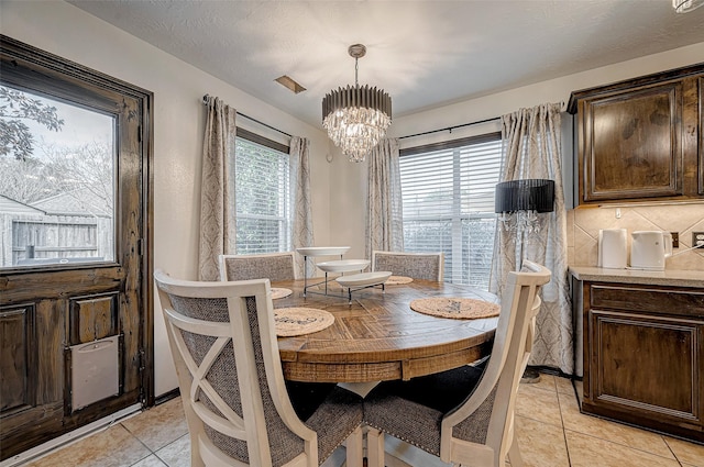 tiled dining room featuring a textured ceiling and an inviting chandelier