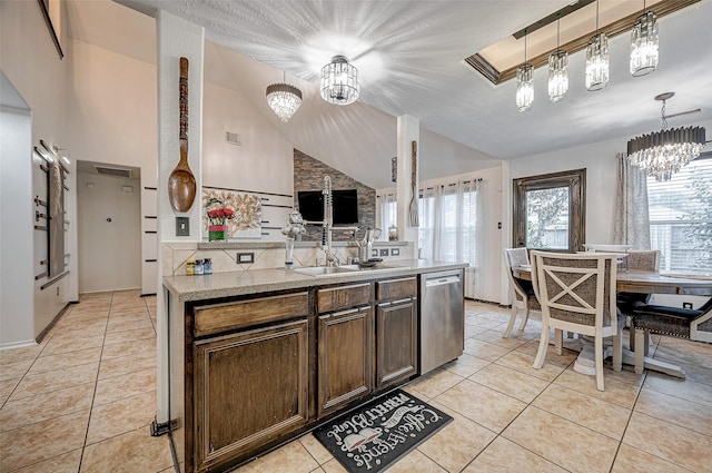 kitchen with an inviting chandelier, stainless steel dishwasher, hanging light fixtures, and light tile patterned floors