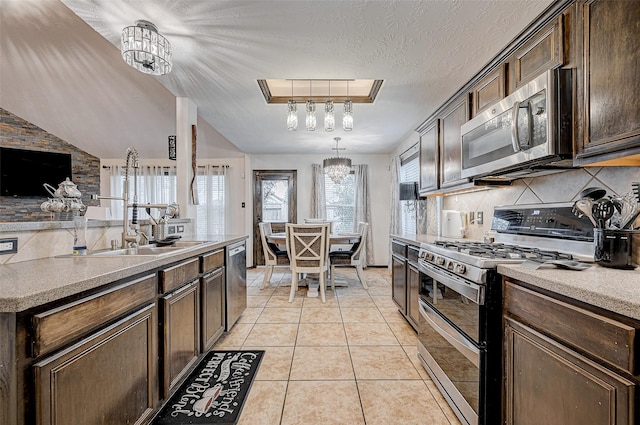 kitchen featuring light tile patterned flooring, appliances with stainless steel finishes, decorative light fixtures, decorative backsplash, and dark brown cabinetry