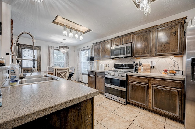 kitchen with pendant lighting, sink, decorative backsplash, stainless steel appliances, and dark brown cabinets