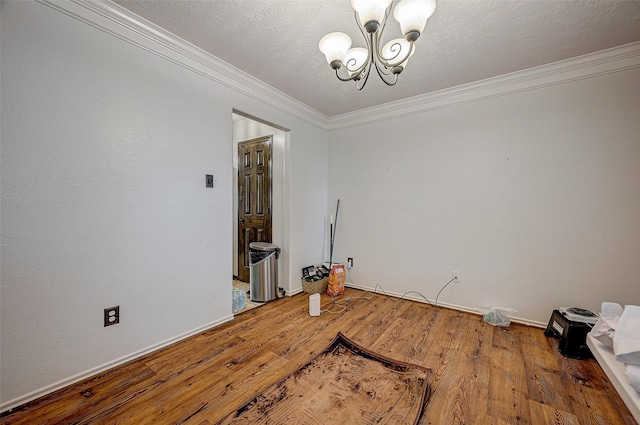 dining space featuring an inviting chandelier, ornamental molding, a textured ceiling, and hardwood / wood-style flooring