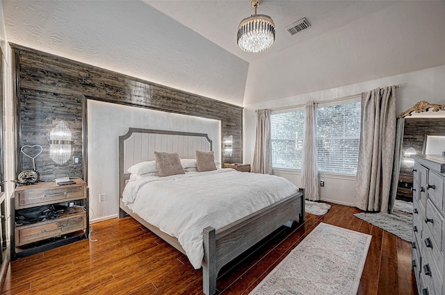 bedroom with dark wood-type flooring, a chandelier, and vaulted ceiling