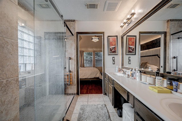 bathroom featuring an enclosed shower, vanity, tile patterned flooring, and a textured ceiling