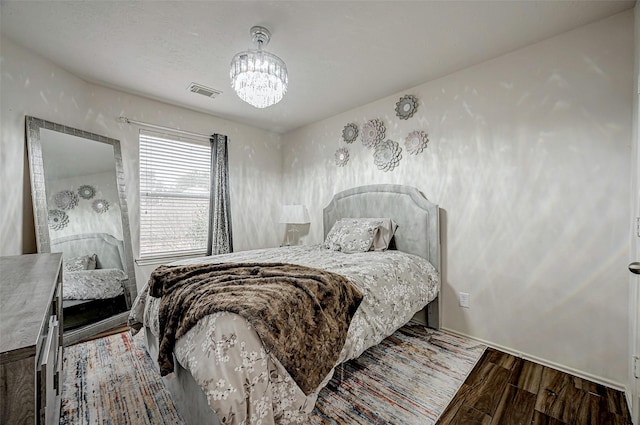 bedroom featuring an inviting chandelier and wood-type flooring