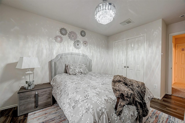 bedroom with a closet, dark hardwood / wood-style floors, and a chandelier