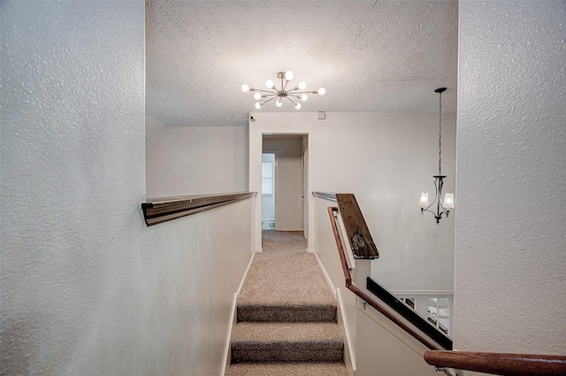 staircase with carpet, a textured ceiling, and a chandelier