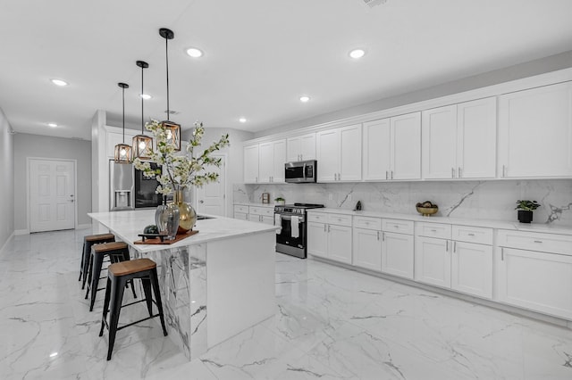 kitchen featuring white cabinets, decorative light fixtures, a center island, and stainless steel appliances