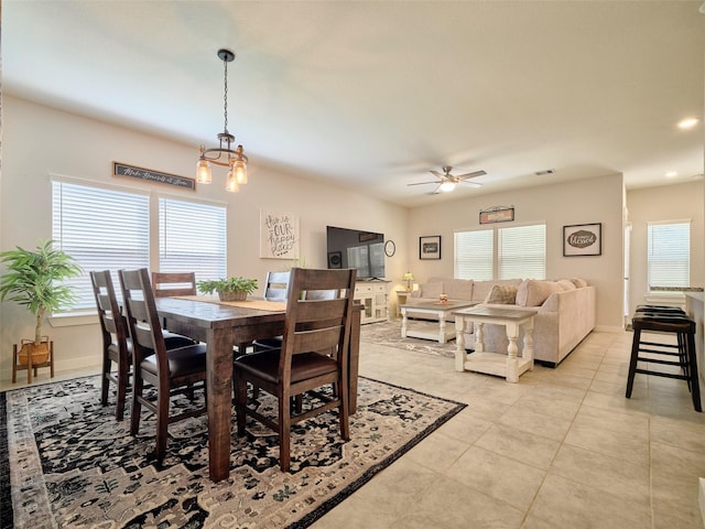 dining room with ceiling fan with notable chandelier, plenty of natural light, and light tile patterned flooring