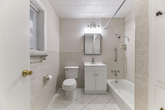 full bathroom with tile walls, tiled shower / bath combo, vanity, toilet, and tile patterned floors