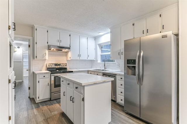 kitchen featuring sink, appliances with stainless steel finishes, white cabinets, a kitchen island, and light wood-type flooring