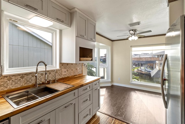 kitchen featuring wooden counters, sink, decorative backsplash, gray cabinets, and stainless steel refrigerator