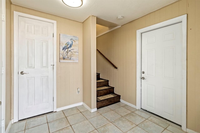 foyer with light tile patterned floors and wood walls