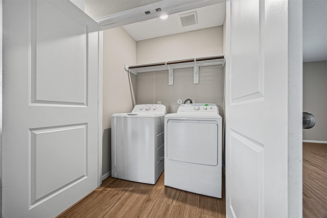 washroom with hardwood / wood-style floors, a textured ceiling, and washing machine and dryer