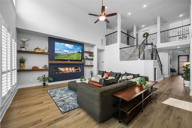 living room featuring wood-type flooring, a towering ceiling, and ceiling fan