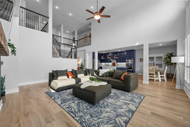 living room with ceiling fan, wood-type flooring, and a high ceiling