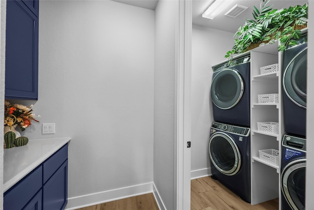 washroom with cabinets, stacked washer and dryer, and light hardwood / wood-style flooring