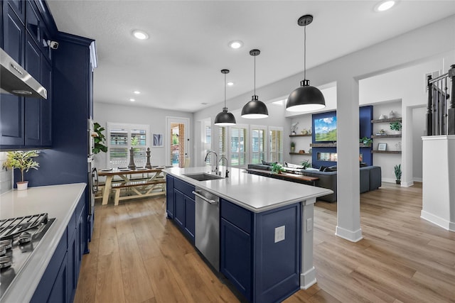 kitchen featuring a kitchen island with sink, blue cabinets, hanging light fixtures, sink, and stainless steel appliances