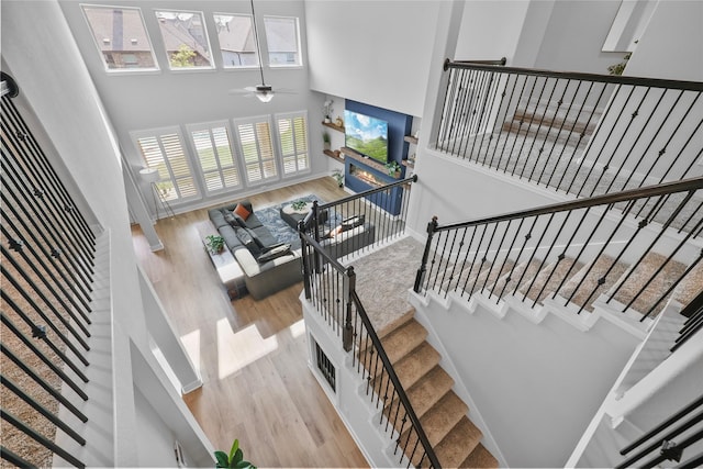 stairway with hardwood / wood-style flooring, ceiling fan, and a high ceiling