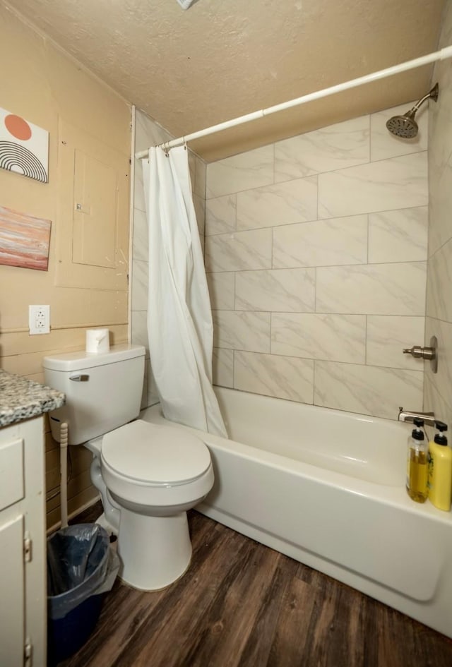 full bathroom featuring vanity, hardwood / wood-style flooring, toilet, a textured ceiling, and shower / tub combo with curtain