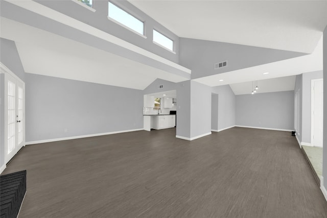 unfurnished living room featuring french doors, high vaulted ceiling, and dark wood-type flooring