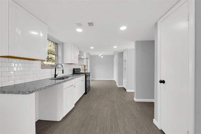 kitchen featuring gas stove, sink, dark hardwood / wood-style flooring, dark stone counters, and white cabinets