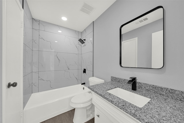 full bathroom featuring vanity, wood-type flooring, tiled shower / bath combo, and toilet