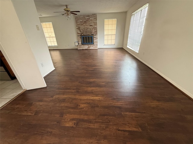 unfurnished living room featuring dark hardwood / wood-style flooring, ceiling fan, and a fireplace