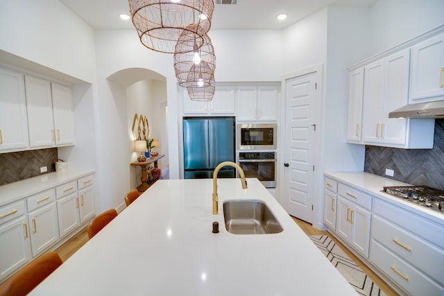 kitchen featuring tasteful backsplash, pendant lighting, sink, white cabinetry, and stainless steel appliances