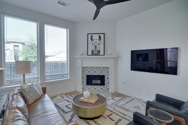 living room with ceiling fan, wood-type flooring, and a tiled fireplace