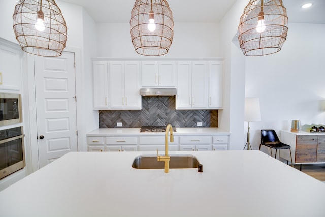 kitchen featuring sink, stainless steel appliances, white cabinetry, and hanging light fixtures